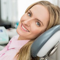 woman smiling at the camera while sitting in dental chair