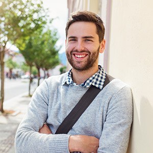 man with laptop bag smiling outdoors after bad breath treatment
