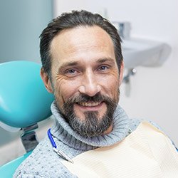 man with turtle neck smiling in dental chair