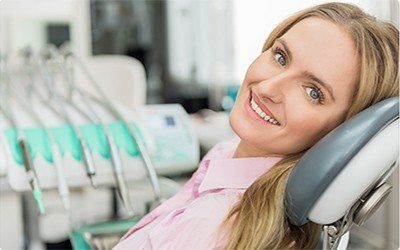 Smiling woman in pink blouse leaning back in dental chair