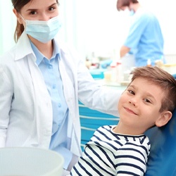 A little boy smiling in the dental chair alongside his dentist