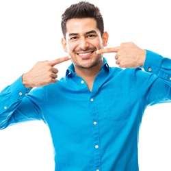 A young man pointing to his smile with dental crowns in Albuquerque