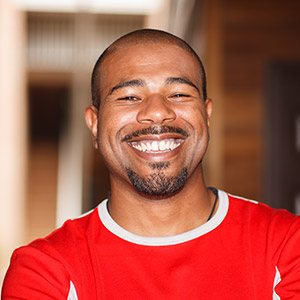 Man in red tee shirt smiling after gum disease treatment in Albuquerque