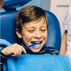 kid brushing teeth in dental chair