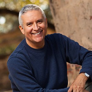 Man in blue sweater smiling after restorative dentistry in Albuquerque