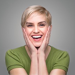 Woman with veneers in Albuquerque smiling and touching her face