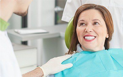 Older woman in dental chair smiling at her dentist
