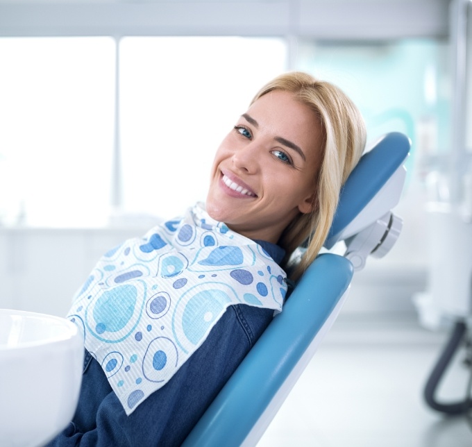 Blonde woman smiling and leaning back in dental chair