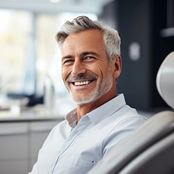 Middle aged man smiling with dental bridge while in the dental chair