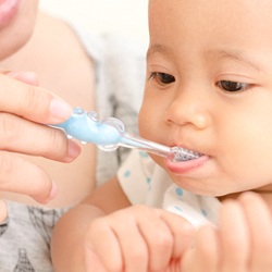 A person brushing their baby’s teeth