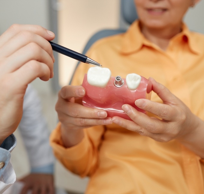 Patient holding a dental implant model