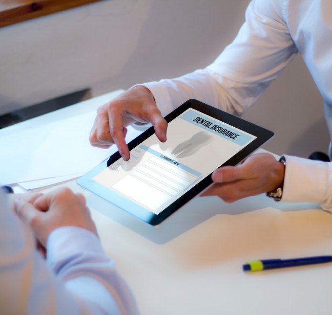 Dentist holding a tablet with form for dental insurance in Albuquerque