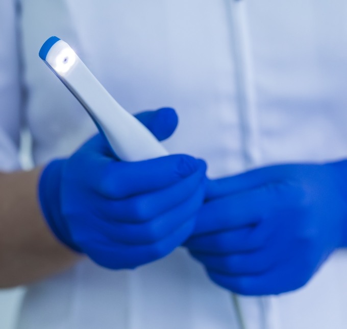 Gloved hand holding an intraoral camera
