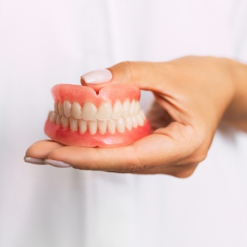 Hand holding two full dentures