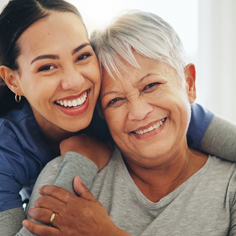 Older woman smiling alongside a young woman