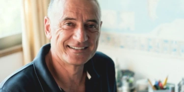 Wider shot of smiling man with grey hair
