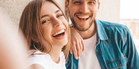 Man and woman leaning against wall smiling