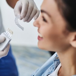 A dentist holding a clear aligner while the patient smiles