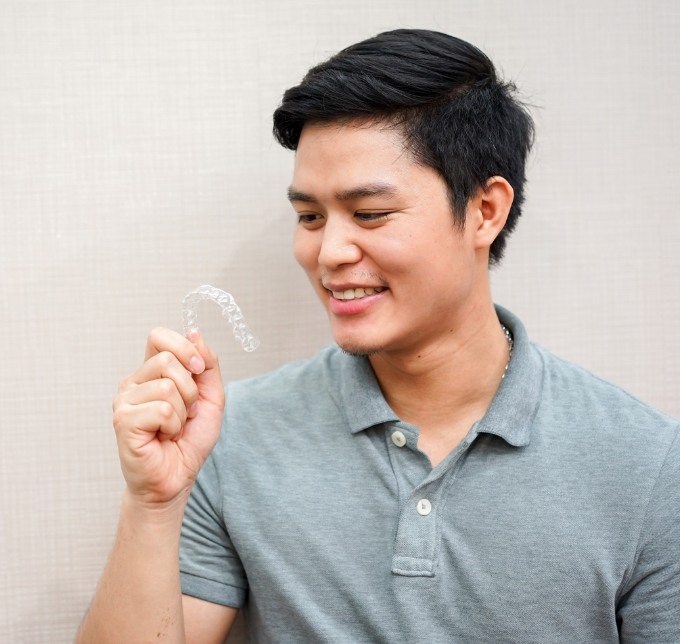 Young man looking at an Invisalign aligner