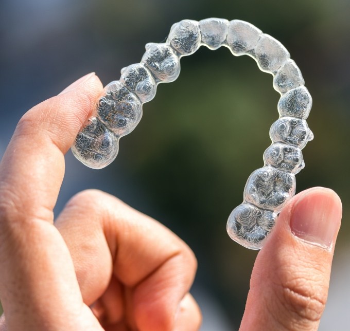Hand holding an Invisalign aligner