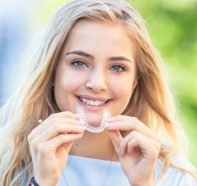 Blonde woman putting in an Invisalign aligner