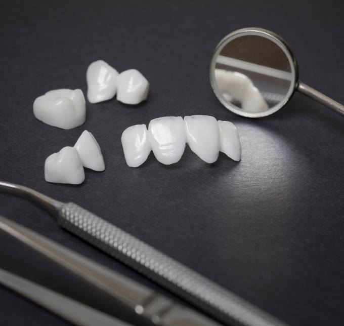 Dental instruments lying on black surface next to metal free dental restorations in Albuquerque