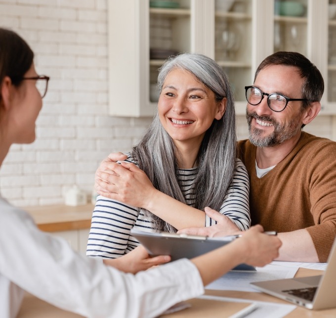 Older couple speaking to dentist who is showing them forms