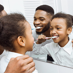 Father and child brushing their teeth together