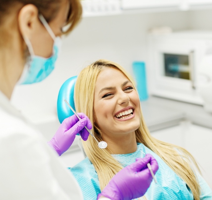 Blonde woman laughing in dental chair with dentist nearby