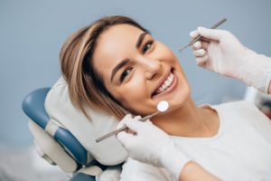 a young woman lying back in a dentist’s chair preparing to have her teeth checked and cleaned