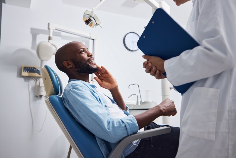male patient in the treatment chair talking to dentist